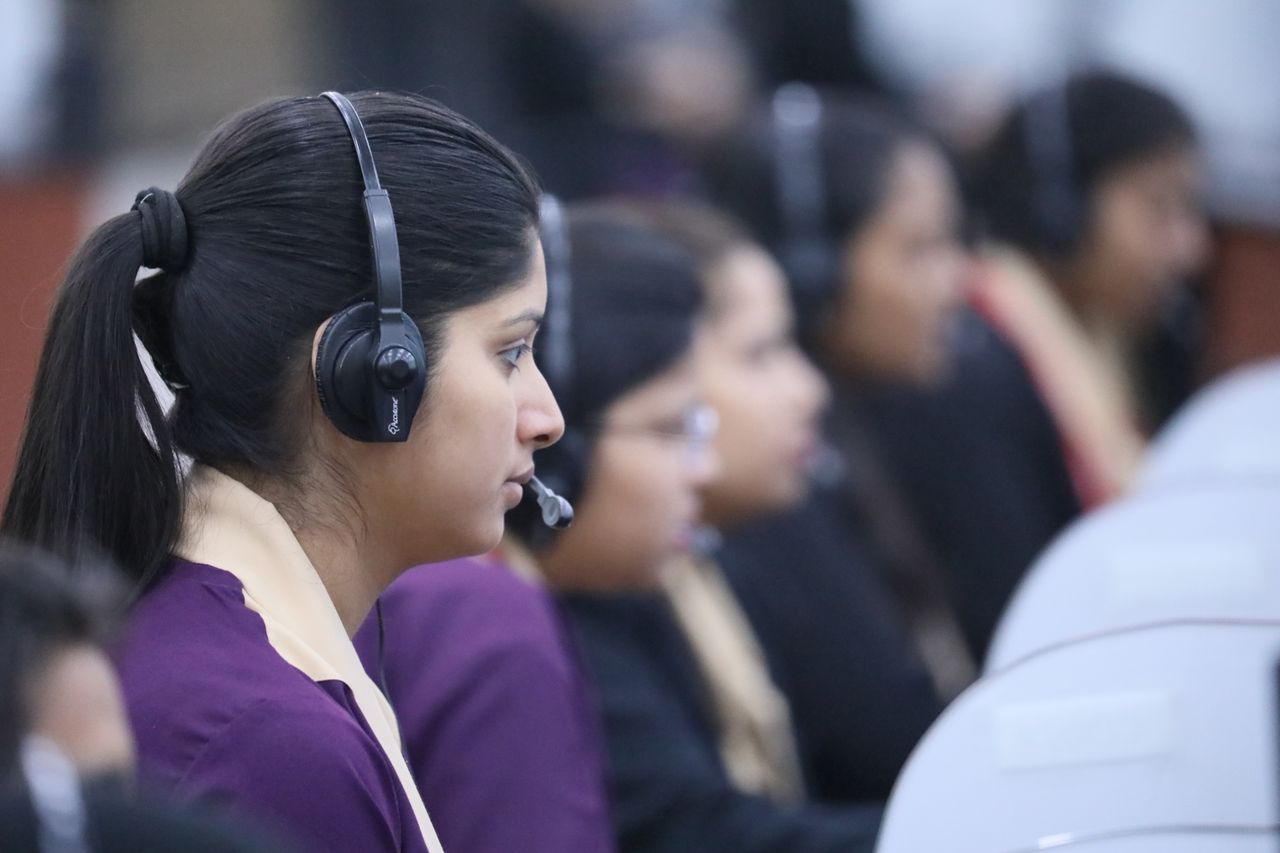 Profile view of a call center agent wearing a headset, focused and working in an office environment.